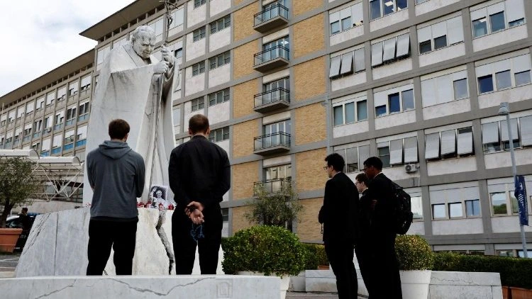 Sacerdotes rezam diante de uma estátua durante a internação do papa Leão XIV